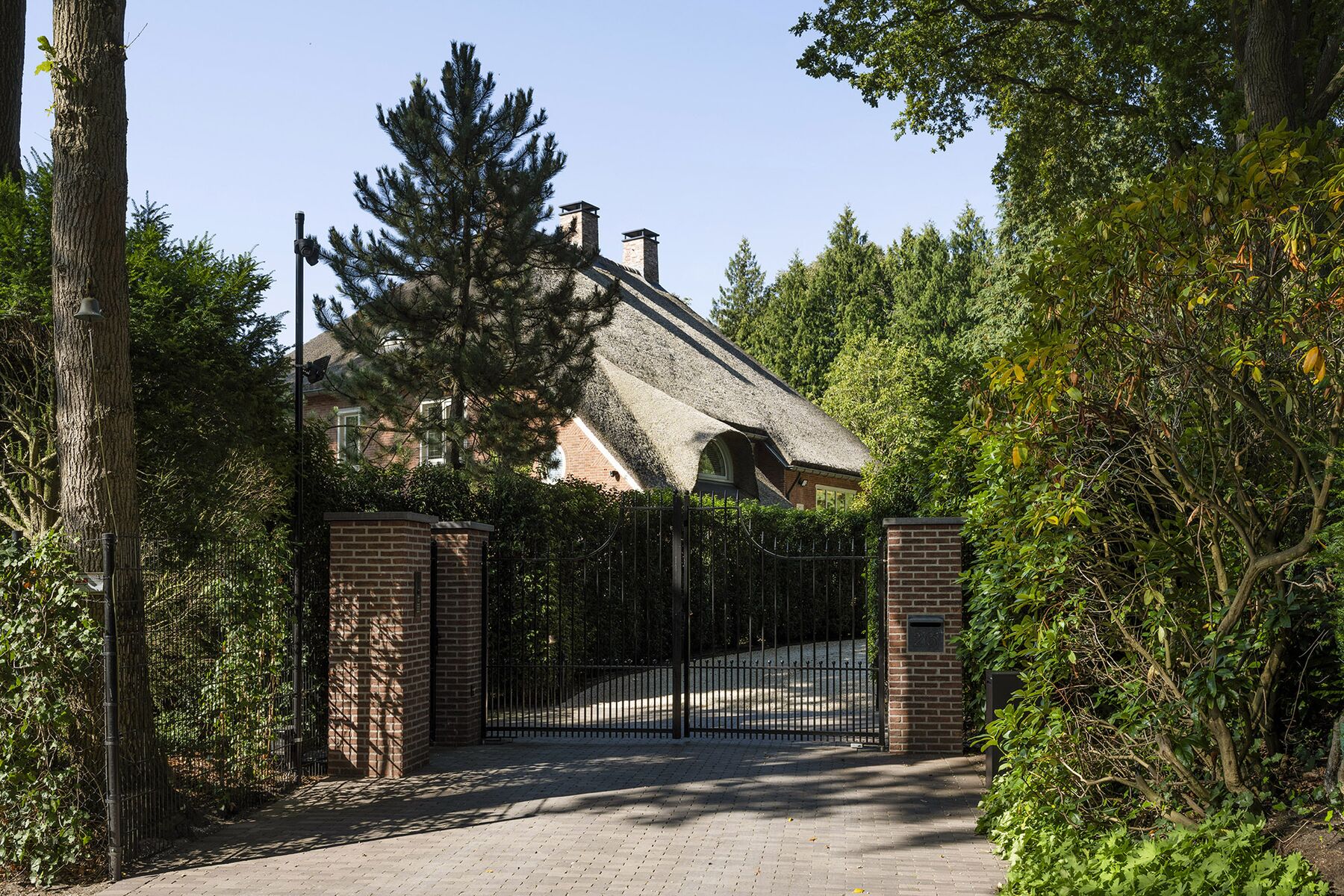 Smeedijzeren poort met klinkeroprit naar een landhuis