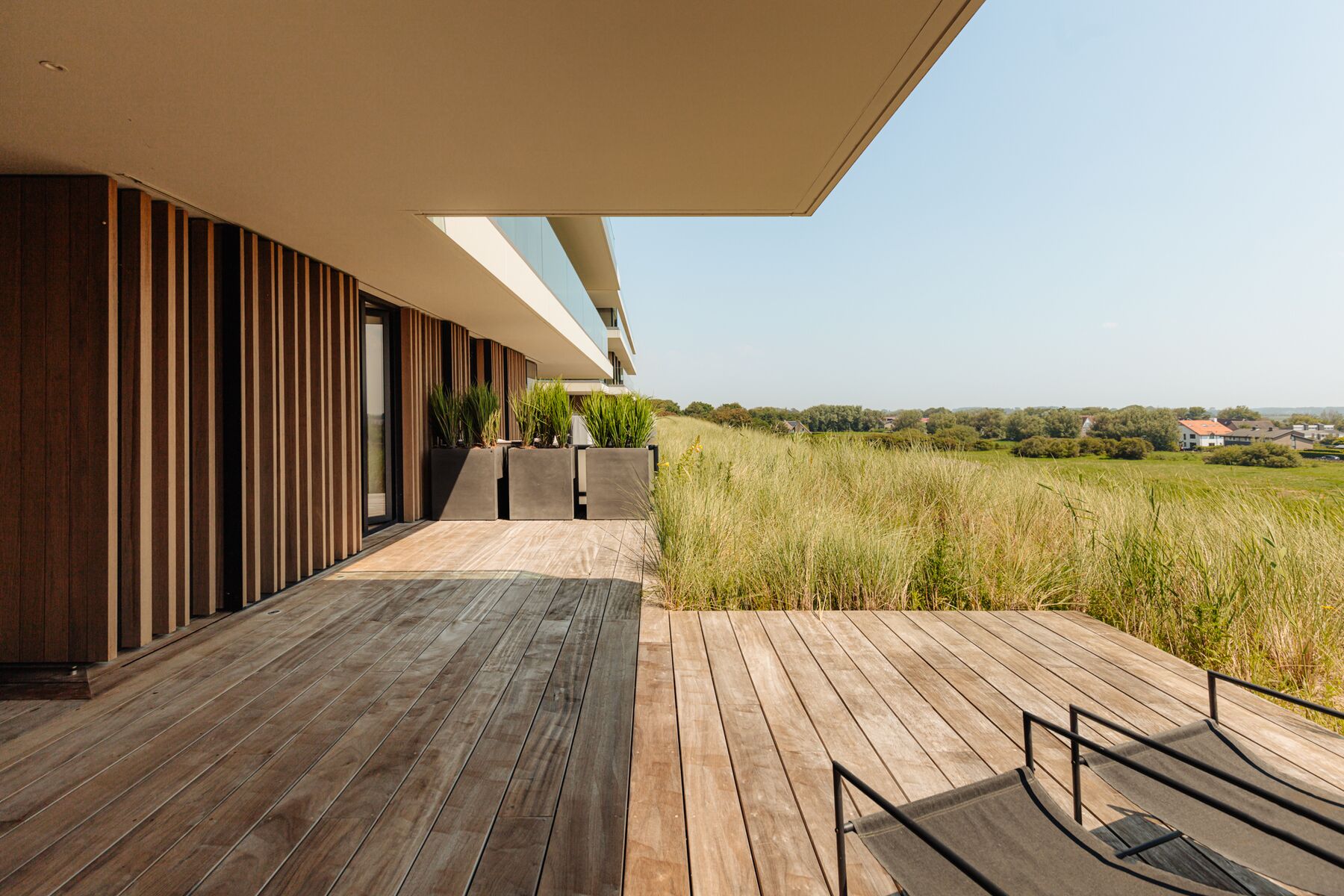 Terras met houten lamellen en zicht op de duinen