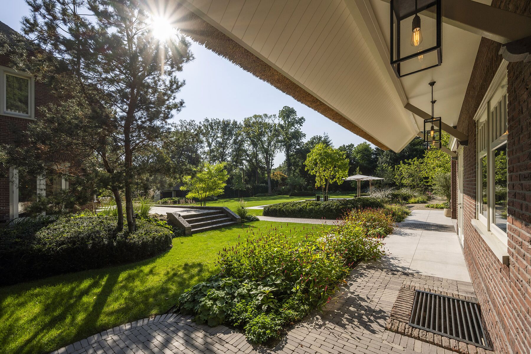Veranda met lantaarn en zicht over de tuin in tegenlicht